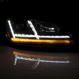 LED-Auto-Scheinwerfer bei Nacht mit weißem Tagfahrlicht und aktivem, amberfarbenem Blinker. Deutliche Reflexion auf der Oberfläche.